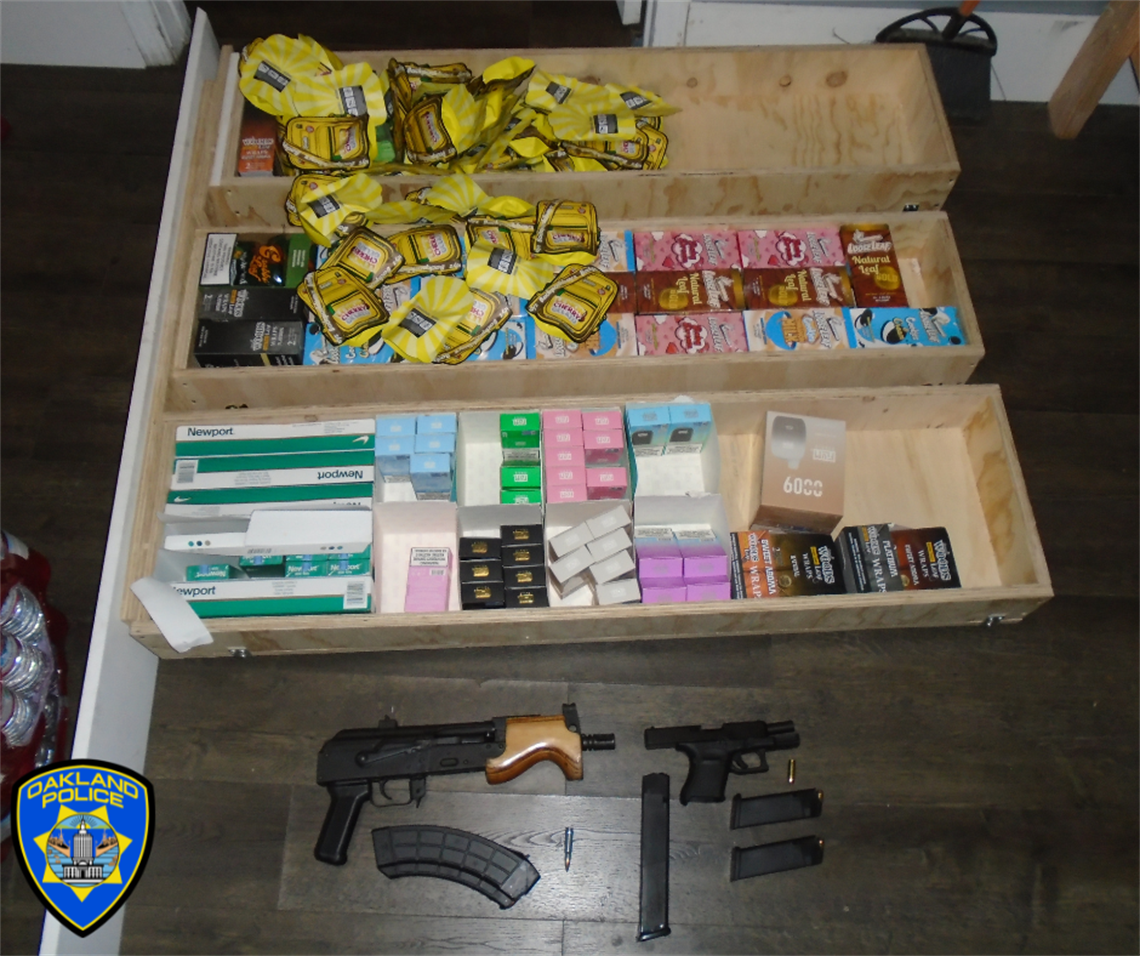 Photo of illegal assault weapon, along with a handgun, multiple pre-packaged bags of marijuana, untaxed cigarettes, and flavored tobacco products.