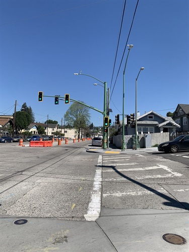This image shows new traffic signals installed alongside old signals on 14th Ave. There is a median under construction below the signals.