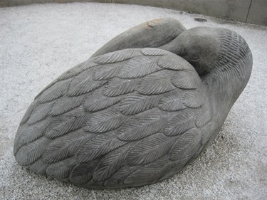 Grey stone sculpture of a Clapper Rail bird resting.