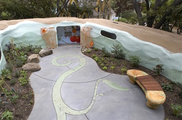 A courtyard with a bench and plants near a play area. 