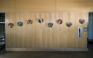 Artwork printed on medallions suspended along a wall inside a recreation center.