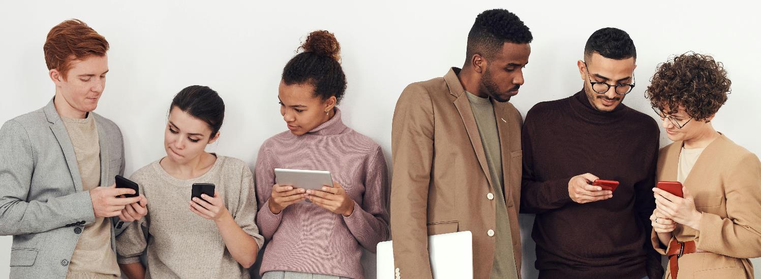 Group of people looking at their phones and tablets.
